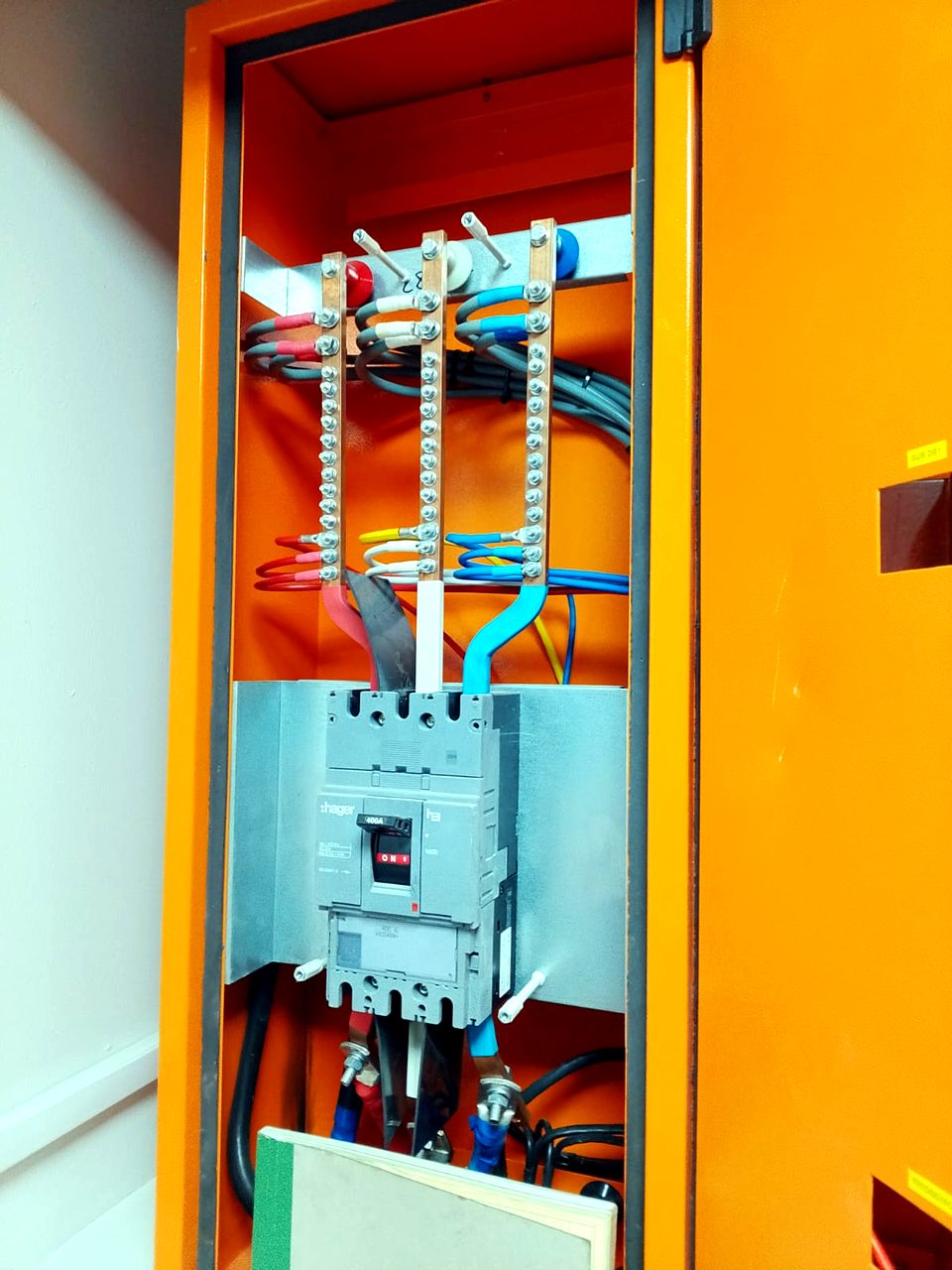 Open distribution board interior showing a Hager 400A circuit breaker, busbars, and colour-coded wiring.