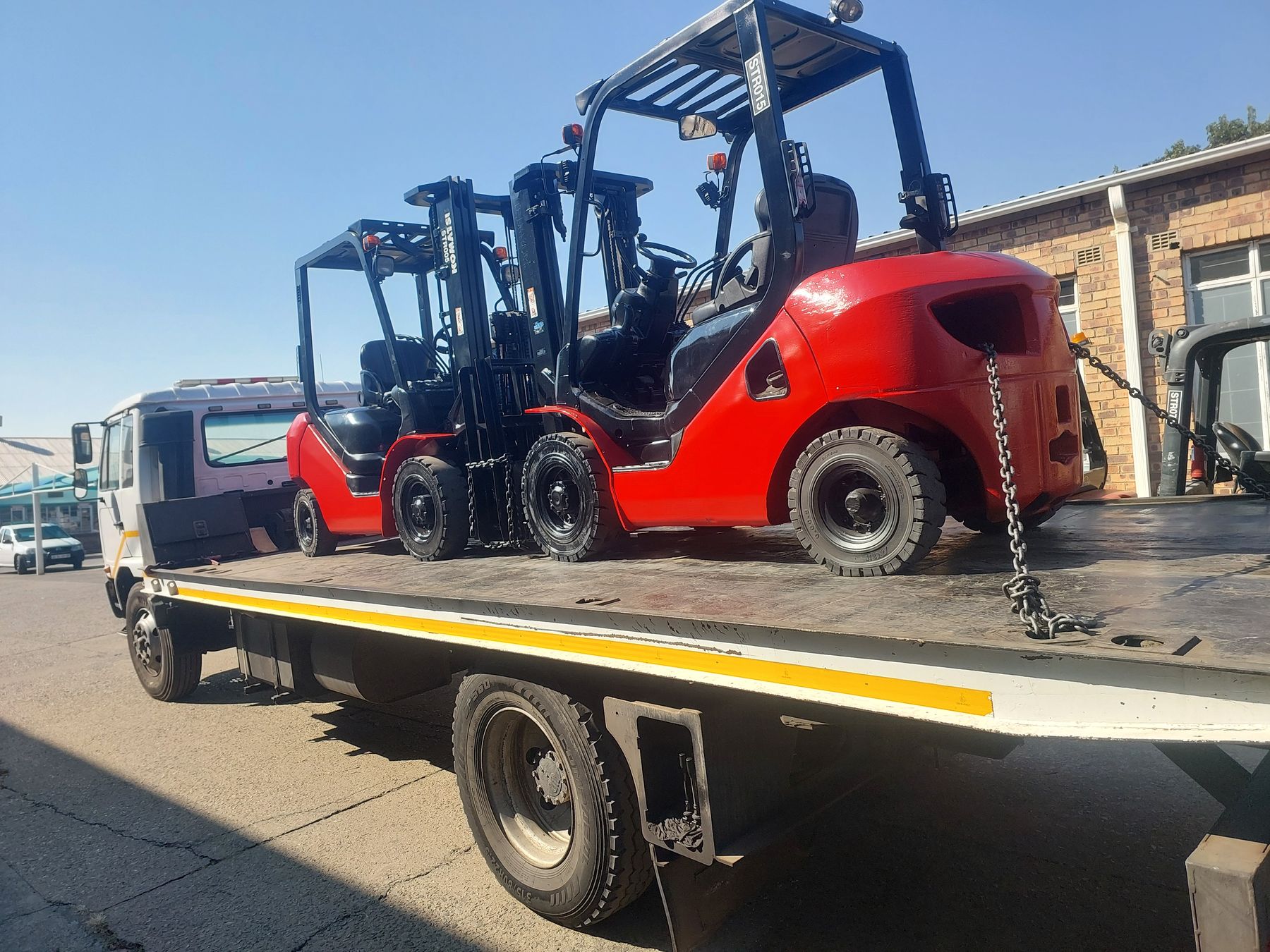 Rental forklifts loaded on an Ampwise flatbed truck for delivery to a customer site.